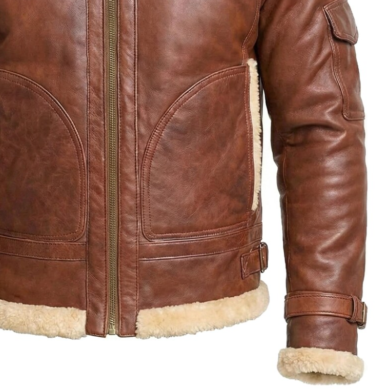 Close-up of a brown leather jacket with a cream shearling lining, showing the front zipper, pocket details, and ribbed cuffs and hem.