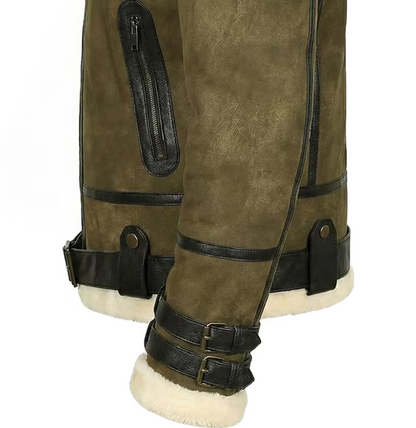 Close-up of olive green suede aviator-style boots with black leather trim, straps, buckles, and a cream shearling lining visible at the cuffs and sole.