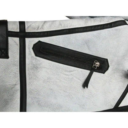 Close-up of a light gray textured leather bag with black trim and a black zippered pocket featuring a silver-tone metal pull.