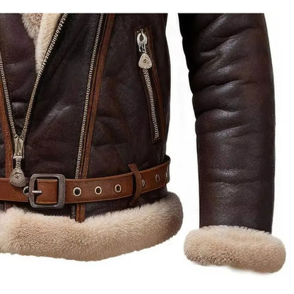 Close-up of a dark brown leather aviator jacket with a thick beige shearling lining, featuring a zippered front, belt with silver buckle, and ribbed sleeve.