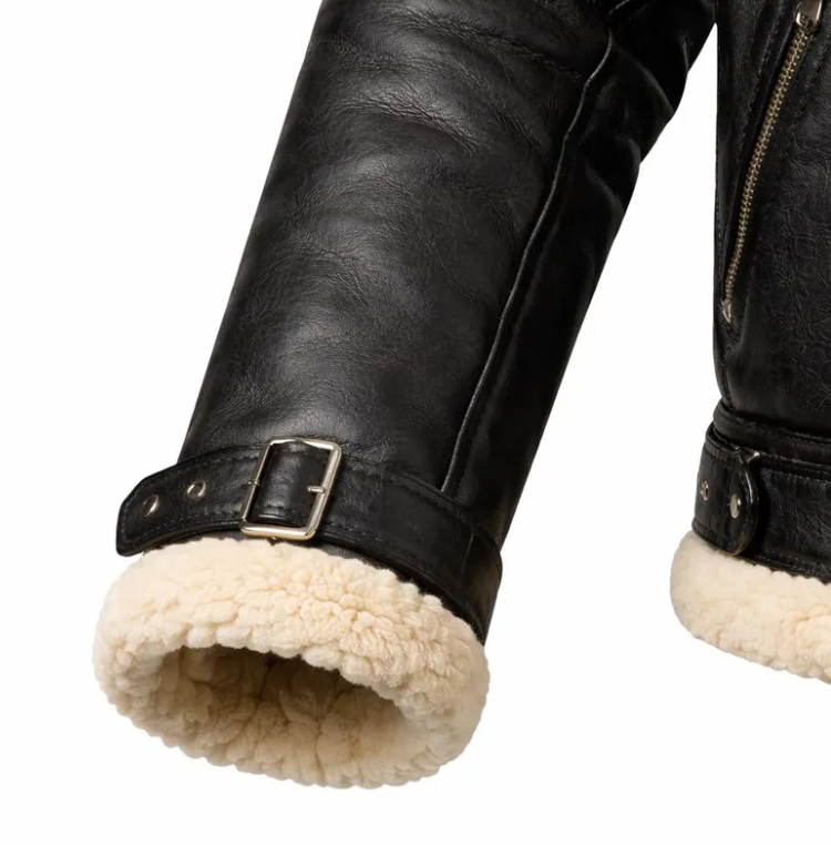 Close-up of a black leather jacket sleeve with a thick cream shearling lining and a silver buckle strap, shown against a white background.